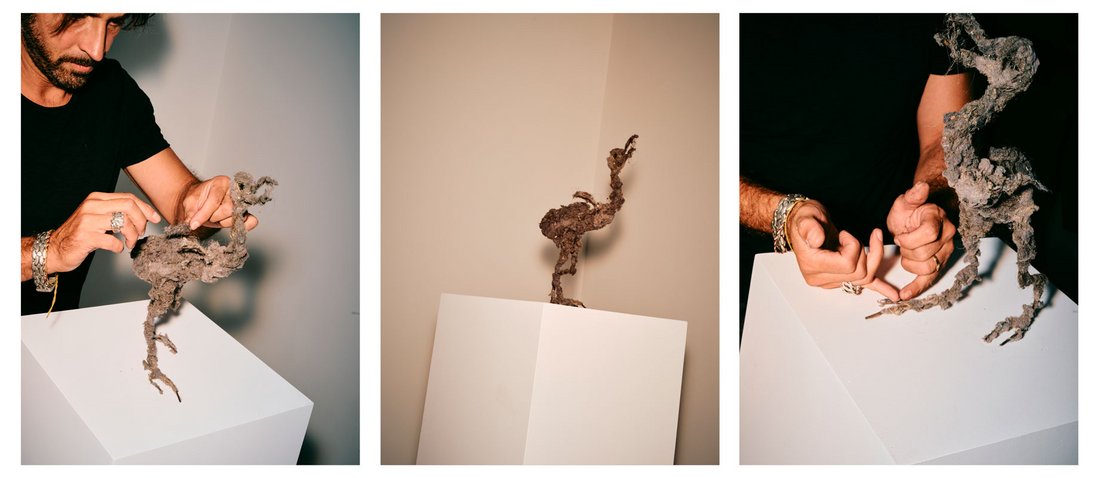 Trois vues de Lionel Sabatté en train de travailler une sculpture installée sur un socle blanc. L’artiste ajuste minutieusement une pièce composée de matières organiques et de poussière agglomérée, dont la forme évoque une créature fragile et étrange. La lumière met en valeur la texture brute et la délicatesse de son geste.