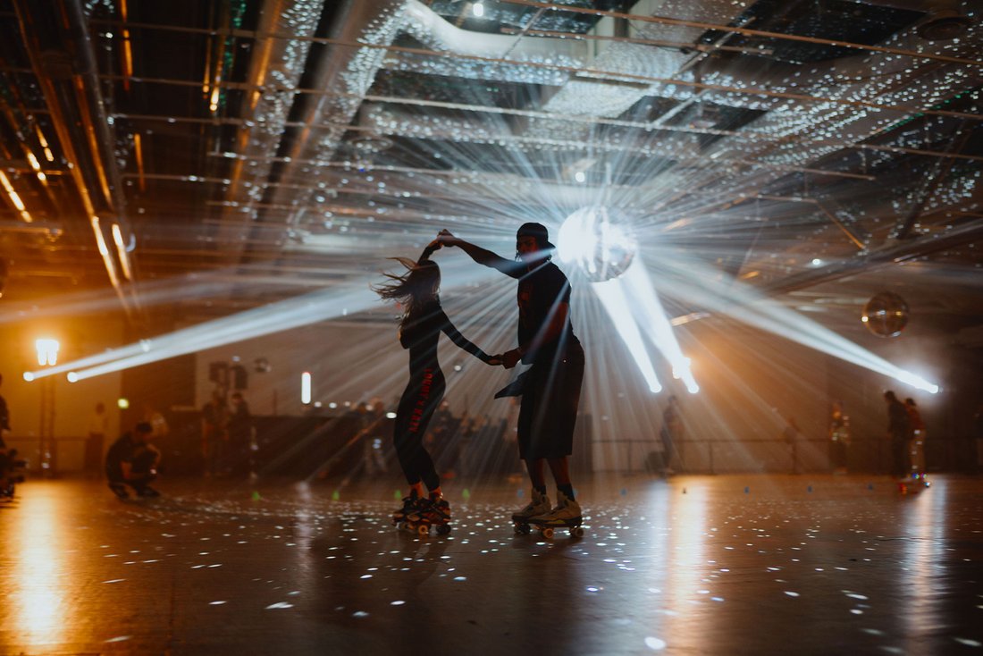 Au niveau 6 du Centre Pompidou, la soirée "Because Beaubourg" transforme l’espace en roller disco futuriste. Deux patineurs virevoltent sous une pluie de lumière émise par une boule à facettes centrale, projetant des éclats sur le sol et le plafond brut. L’ambiance est festive, rétro et immersive, mêlant culture urbaine, art contemporain et musique dans une scénographie lumineuse et électrisante.