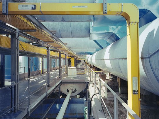 Au niveau 7 du Centre Pompidou, la vue plonge dans les coulisses techniques du toit. Une passerelle métallique longe d’imposantes gaines bleues et conduites jaunes, baignée de lumière naturelle. Cette zone industrielle en hauteur révèle l’ossature high-tech du bâtiment, où l’ingénierie devient paysage urbain.