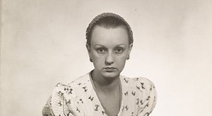 Ce gros plan saisissant extrait du portrait d’Ithell Colquhoun par Man Ray vers 1932 met en lumière l’intensité du regard de l’artiste. Placée face à l’objectif dans une frontalité presque désarmante, elle fixe le spectateur avec une expression grave, introspective et légèrement défiant les conventions de la pose féminine douce attendue à l’époque. Son visage, parfaitement symétrique, est encadré par un filet de cheveux finement ouvragé, révélant un front dégagé et des sourcils nets, marqués d’une courbe fine et expressive. Ses boucles d’oreilles circulaires ajoutent une touche discrète de raffinement, tandis que la texture de sa robe à motifs papillons, visible sur les épaules et le buste, donne un contraste visuel délicat avec la pureté du fond uni. L’éclairage doux met en valeur les ombres du visage sans le dramatiser, soulignant la rigueur de la composition photographique de Man Ray. Cette image condense à elle seule l’esprit du surréalisme : présence forte, ambiguïté émotionnelle, et tension entre l’individu et le symbole. Elle révèle Ithell Colquhoun comme une femme artiste affirmée, concentrée, profondément moderne pour son temps.