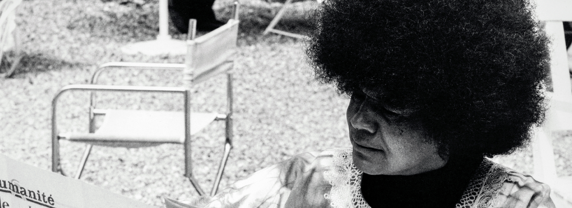 Afro woman reading newspaper, outdoor terrace, l’Humanité newspaper, vintage black and white photo